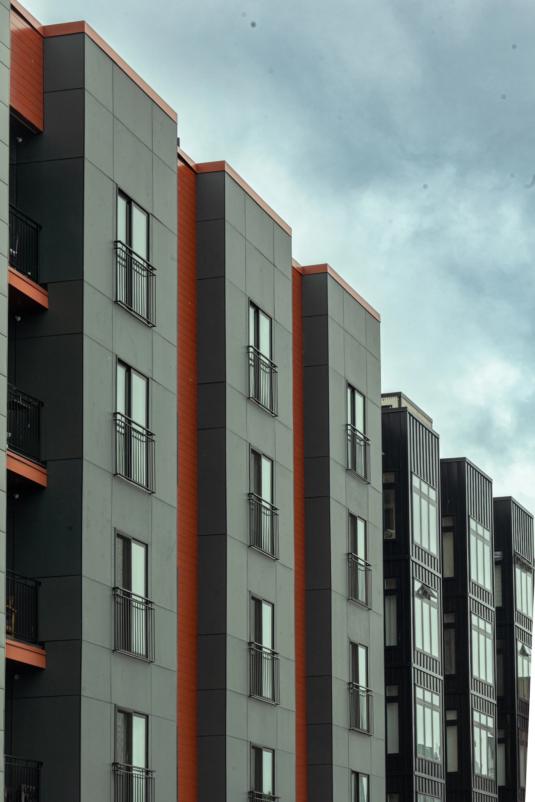 Photograph of residential buildings with gray panels and rust-colored window surrounds in Boston