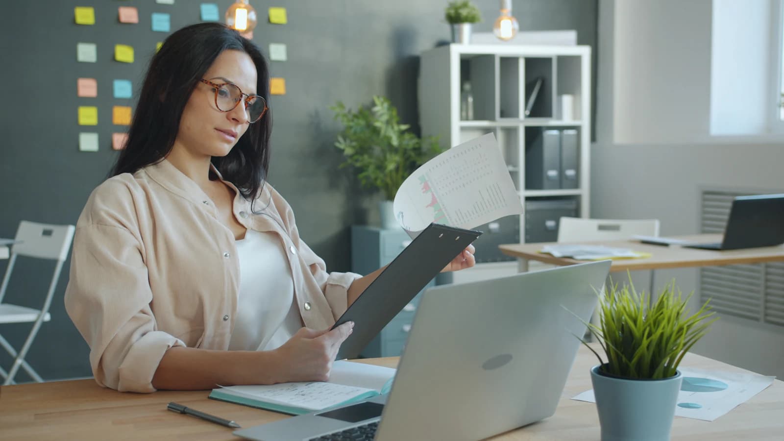 Office professional reviewing documents alongside a laptop